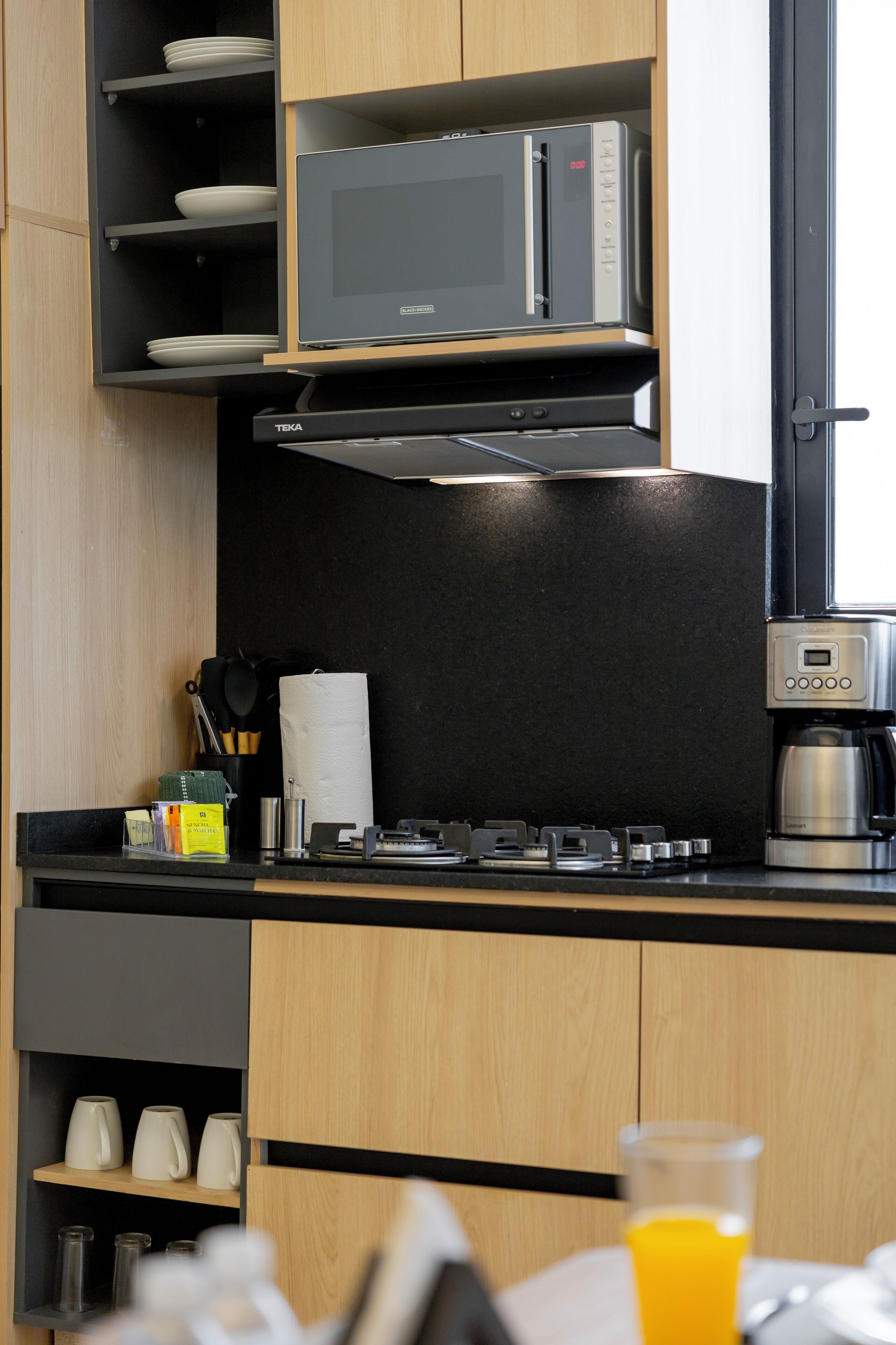 A modern kitchen with a microwave, coffee maker, and various kitchen utensils.