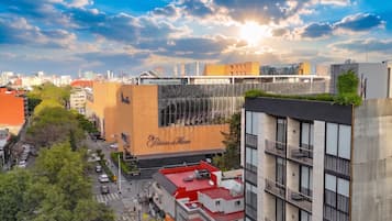 Un edificio moderno con un letrero llamativo que dice 'Palacio de Hierro' y una terraza en la azotea con techo rojo.