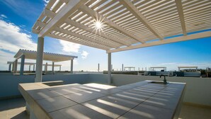 Una terraza al aire libre con una pérgola, una fuente de agua y vistas al mar.