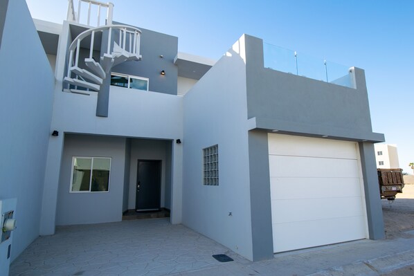 Une maison moderne à deux étages, dotée d’un escalier en colimaçon, d’un garage et d’une allée pavée.