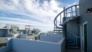 Terraza en la azotea con escalera de caracol, varios niveles y cielo despejado.