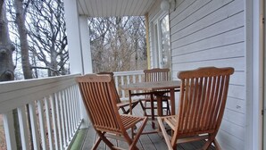 A wooden deck with a table and chairs, surrounded by a white railing.