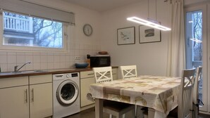 A compact kitchen with a washing machine, a sink, and a dining area with a table and chairs.