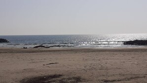 Une plage offrant une vue dégagée sur l’océan et les formations rocheuses lointaines.