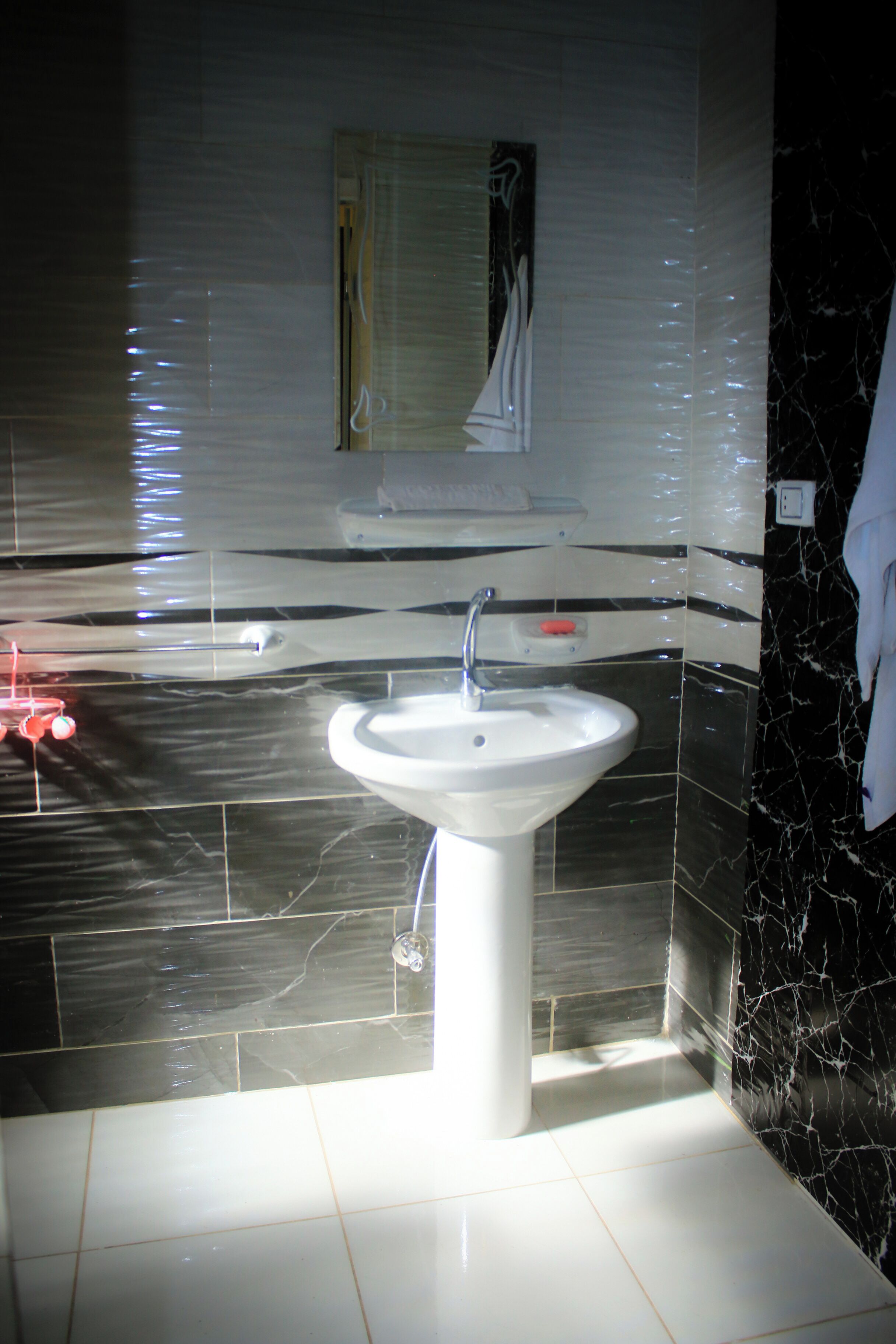 Ein Badezimmer mit einem weißen Waschbecken, Wänden mit Schwarz-Weiß-Fliesen und einem Spiegel über dem Waschbecken.