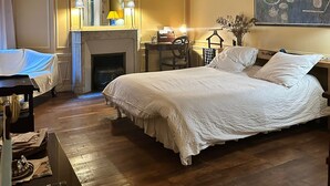 A hotel room with a large bed, a fireplace, a desk, and a painting on the wall. - Golden Triangle x Av Montagine & Champs Elysees (Paris)