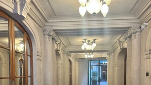 A long, elegant hallway with marble floors and classical columns, leading to a glass door entrance. - Golden Triangle x Av Montagine & Champs Elysees (Paris)