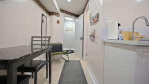 Een kleine keuken met een eethoek, een spoelbakje en een deur naar een andere kamer.