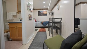 Een ruimtelijk ingerichte leefruimte met kitchenette, een bed, een eethoek en een badkamer.