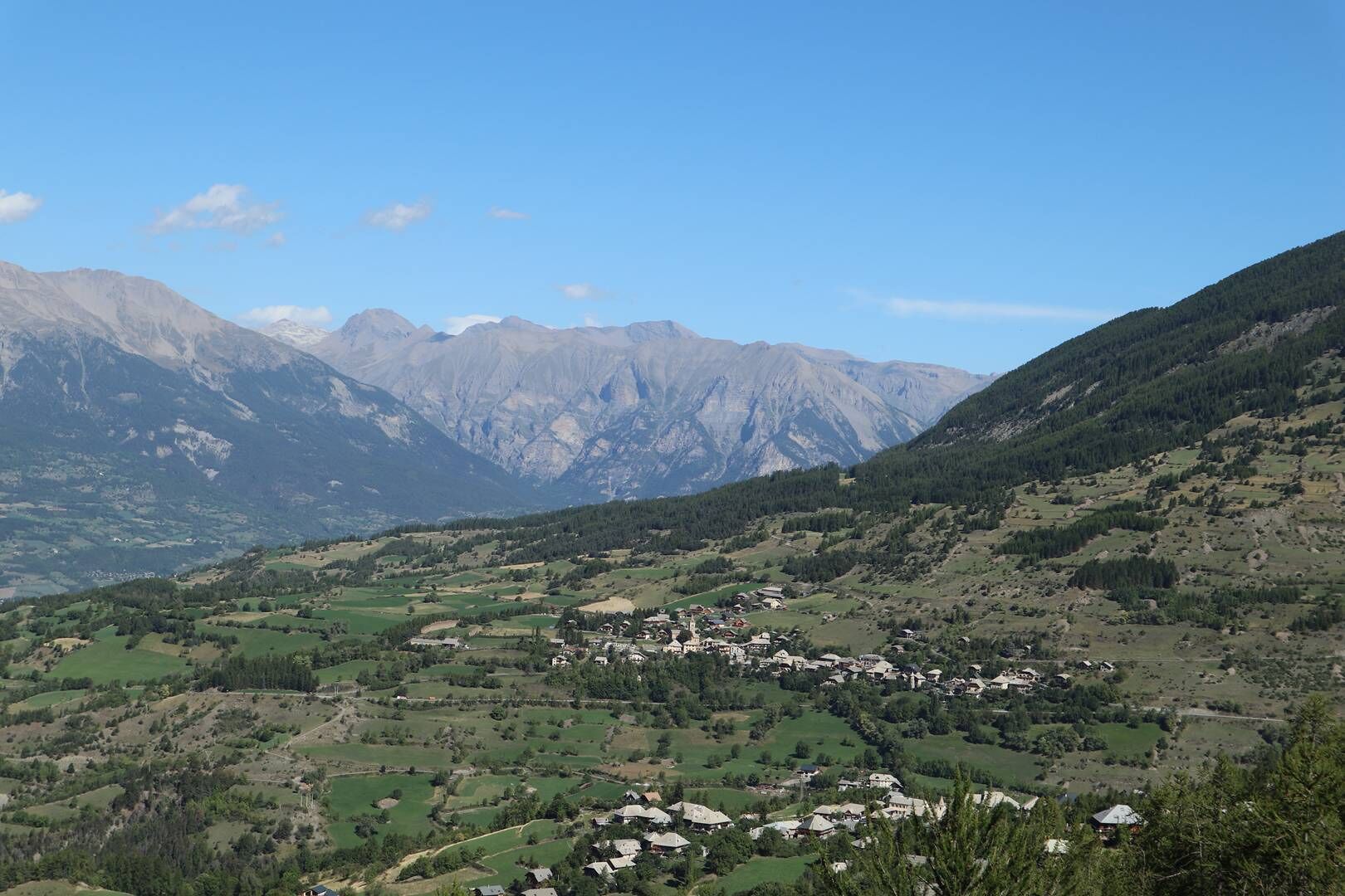 Un paisaje montañoso con un pequeño pueblo ubicado entre campos verdes y casas.