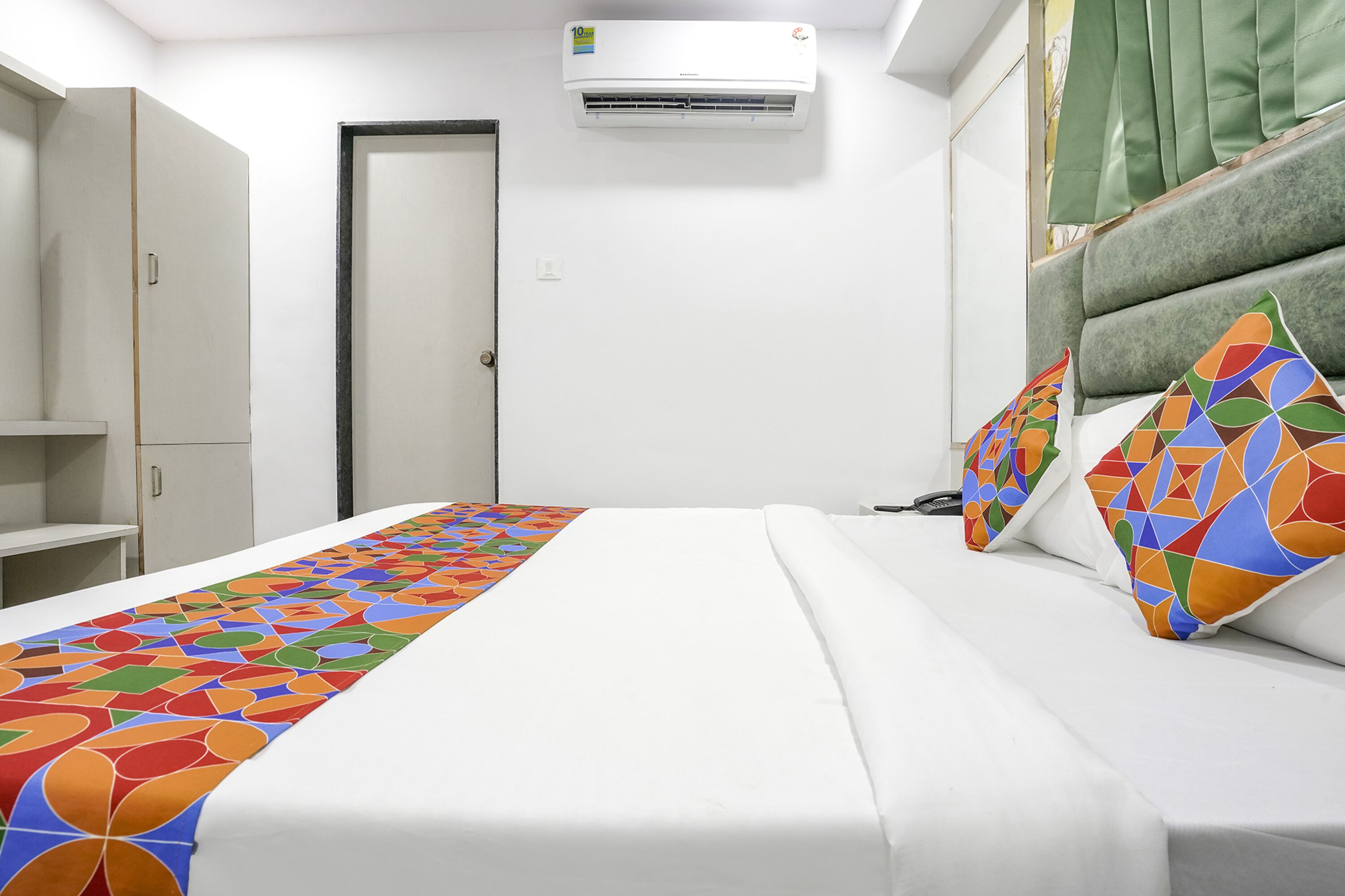 Ein Hotelzimmer mit Bett, Schrank, Klimaanlage und einer Tür.