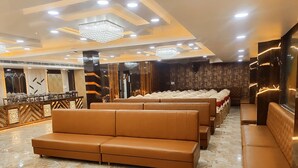 Un moderno vestíbulo de hotel con piso de mármol, asientos de cuero, una zona de buffet e iluminación decorativa.