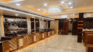 Una zona de bar moderna con suelo de mármol, una barra alargada con iluminación decorativa y un candelabro.