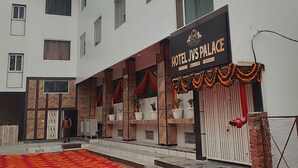 Un hotel llamado 'Hotel JVS Palace', con un cartel, entrada alfombrada en rojo y fachada de edificio moderno.