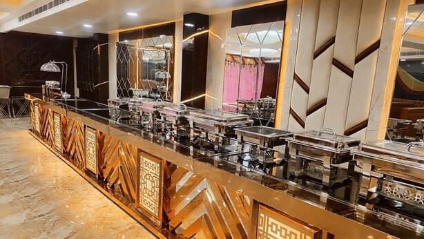 Montaje de bufé con varias estaciones de servicio, piso de mármol y pared decorativa con patrones geométricos.