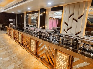 Montaje de bufé con varias estaciones de servicio, piso de mármol y pared decorativa con patrones geométricos.