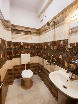 Baño con inodoro, lavamanos y ducha. Las paredes tienen un diseño de azulejos con motivos florales.
