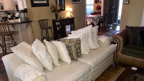A living room with a sofa, a coffee table, and a dining area in the background. - UPSCALE NE TALLAHASSEE QUIET, SECURE RESIDENCE FULLY EQUIPPED (Tallahassee)