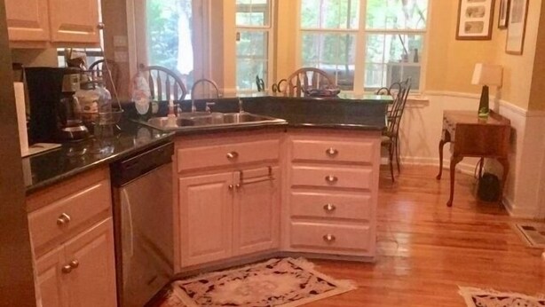 A kitchen with wooden cabinets, a black countertop, and a window with a view of trees. - UPSCALE NE TALLAHASSEE QUIET, SECURE RESIDENCE FULLY EQUIPPED (Tallahassee)