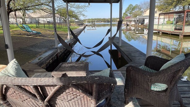 A covered outdoor seating area with wicker furniture and a view of a calm water body. - ❤️ Pickleball, Pool Table, Ping Pong, 4Bd 2bath quiet edition on quiet lake cove. (Granbury)