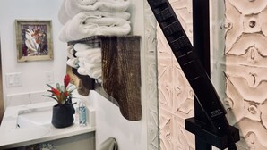 A bathroom with a towel rack, a wall-mounted towel dispenser, a sink, a potted plant, and a framed artwork. - ❤️ Pickleball, Pool Table, Ping Pong, 4Bd 2bath quiet edition on quiet lake cove. (Granbury)