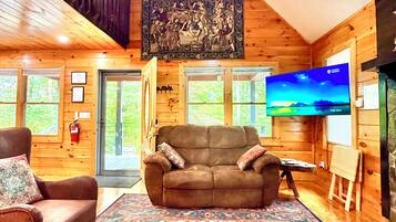 Una stanza accogliente con arredamento in legno, una grande TV a schermo piatto, un divano, un tappeto decorato e un quadro appeso al muro.