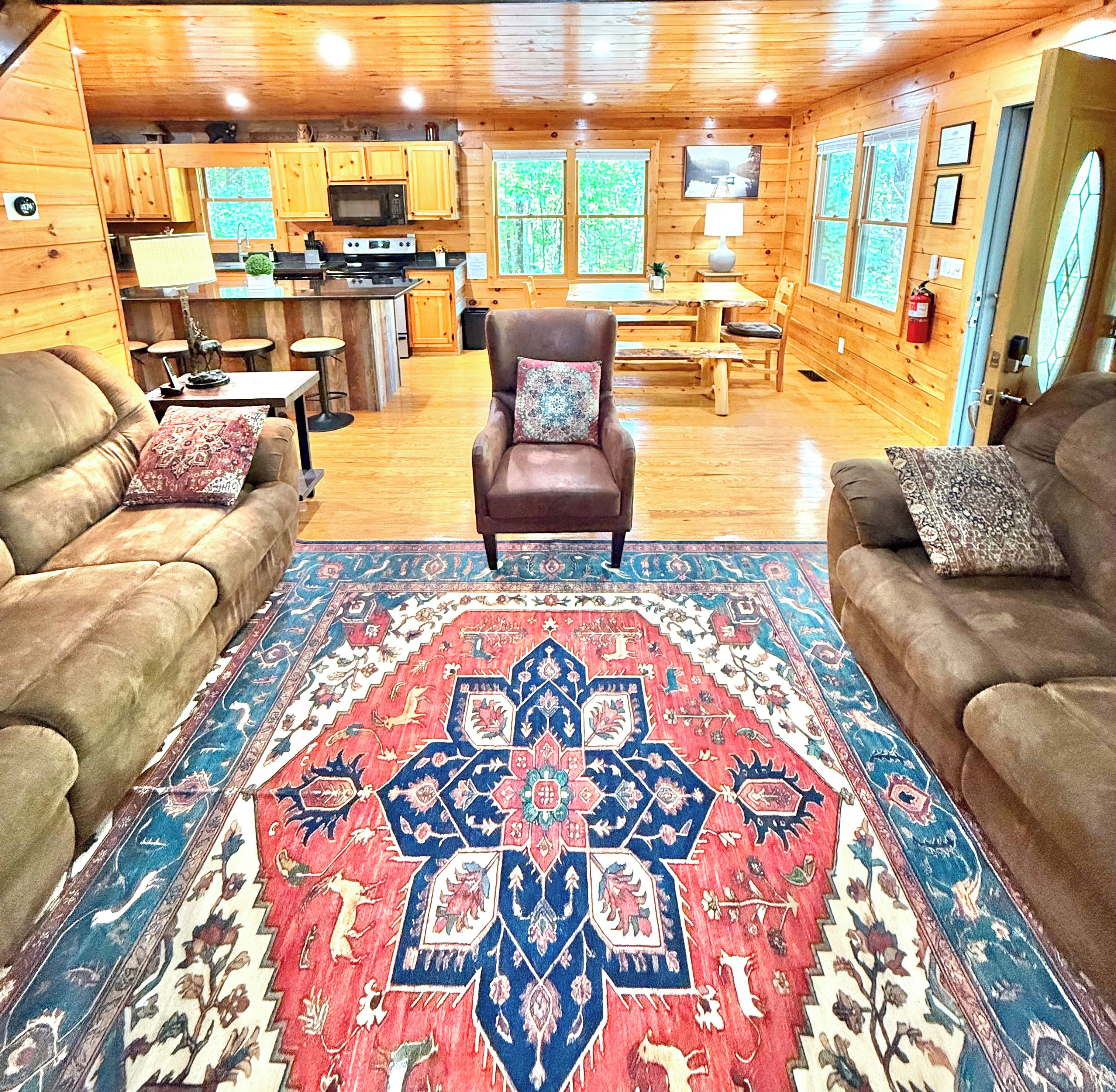A cozy cabin interior with a central seating area, a kitchen, and a dining space.