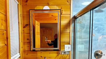 A wooden cabin bathroom with a wooden vanity, a mirror, and a glass shower enclosure.