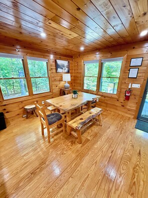 Een houten chalet van binnen, met een eettafel, banken en stoelen.