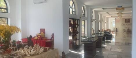 Un vestíbulo amplio con piso pulido, una recepción y exhibición de artesanías locales.