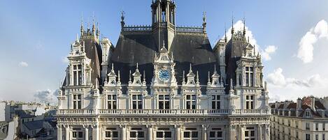 A grand, ornate building with a clock tower, large windows, and intricate architectural details.
