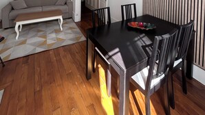 En matplats med ett svart bord och stolar, en vit soffa och en matta med ett geometriskt mönster.