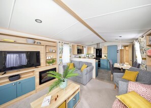 A compact living space with a TV, sofa, dining area, and kitchenette.