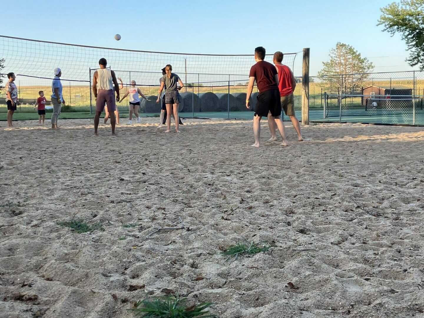 Eine Gruppe von Menschen spielt Beachvolleyball auf einem Sandplatz mit Netz.