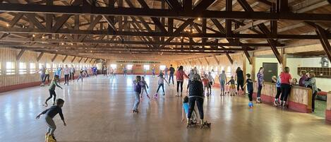 Une vaste patinoire intérieure avec des poutres en bois au plafond et un plancher en bois.