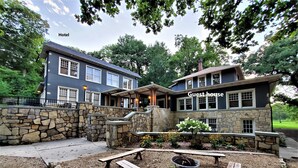 A hotel with a guest house, stone walls, and a patio area with wooden benches and a fire pit.