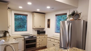 A kitchen with white cabinets, a stainless steel refrigerator, a built-in oven, and granite countertops.