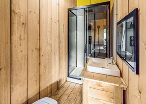 Ein Badezimmer einer Holzhütte mit Duschkabine aus Glas, einem Waschbecken und einem Spiegel.