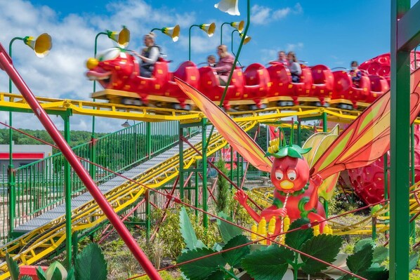 Des montagnes russes avec des wagons rouges et une grande figure de dragon.