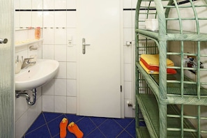 A bathroom with a white sink, a blue tiled floor, and a green metal shelf unit.