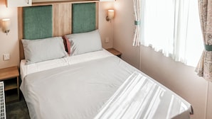 A hotel room with a bed, bedside tables, a wardrobe, and a window with curtains. - 3 bedroom accommodation in Chapel St Leonards, Skegness (Chapel St Leonards, Skegness)