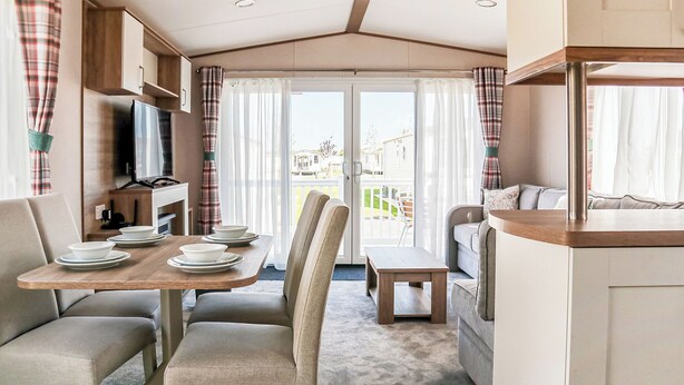 A caravan interior with a dining area, seating, and a kitchenette. - 3 bedroom accommodation in Chapel St Leonards, Skegness (Chapel St Leonards, Skegness)
