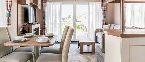A caravan interior with a dining area, seating, and a kitchenette.