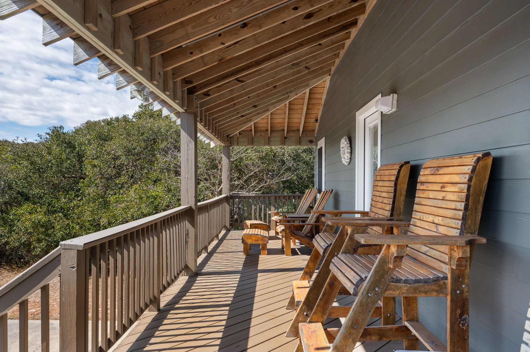 Eine Holzterrasse mit Sitzgelegenheiten und Blick auf die umliegenden Bäume.