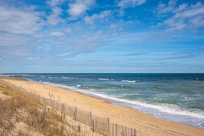 A beach with a wooden fence and waves.