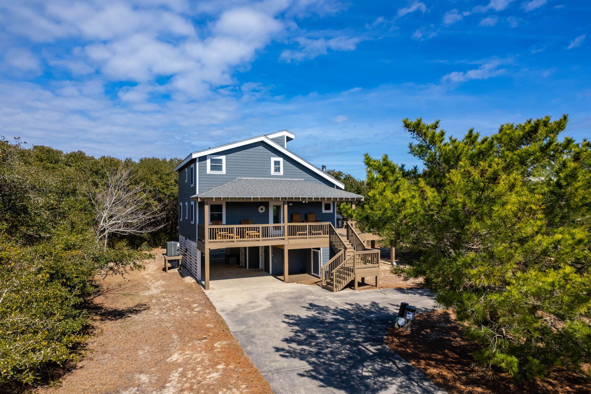 A two-story house with a covered porch and a staircase leading to a deck.