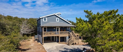 A two-story house with a covered porch and a staircase leading to a deck.