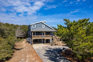 A two-story house with a covered porch and a staircase leading to a deck.