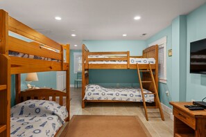 A room with bunk beds, a desk, a chair, and a television. - Reel Catch: Hot Tub, Close to the beach in Southern Shores! (Southern Shores)