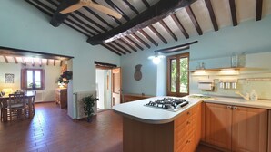 Un'ampia cucina con isola centrale, mobili in legno e ventilatore a soffitto.